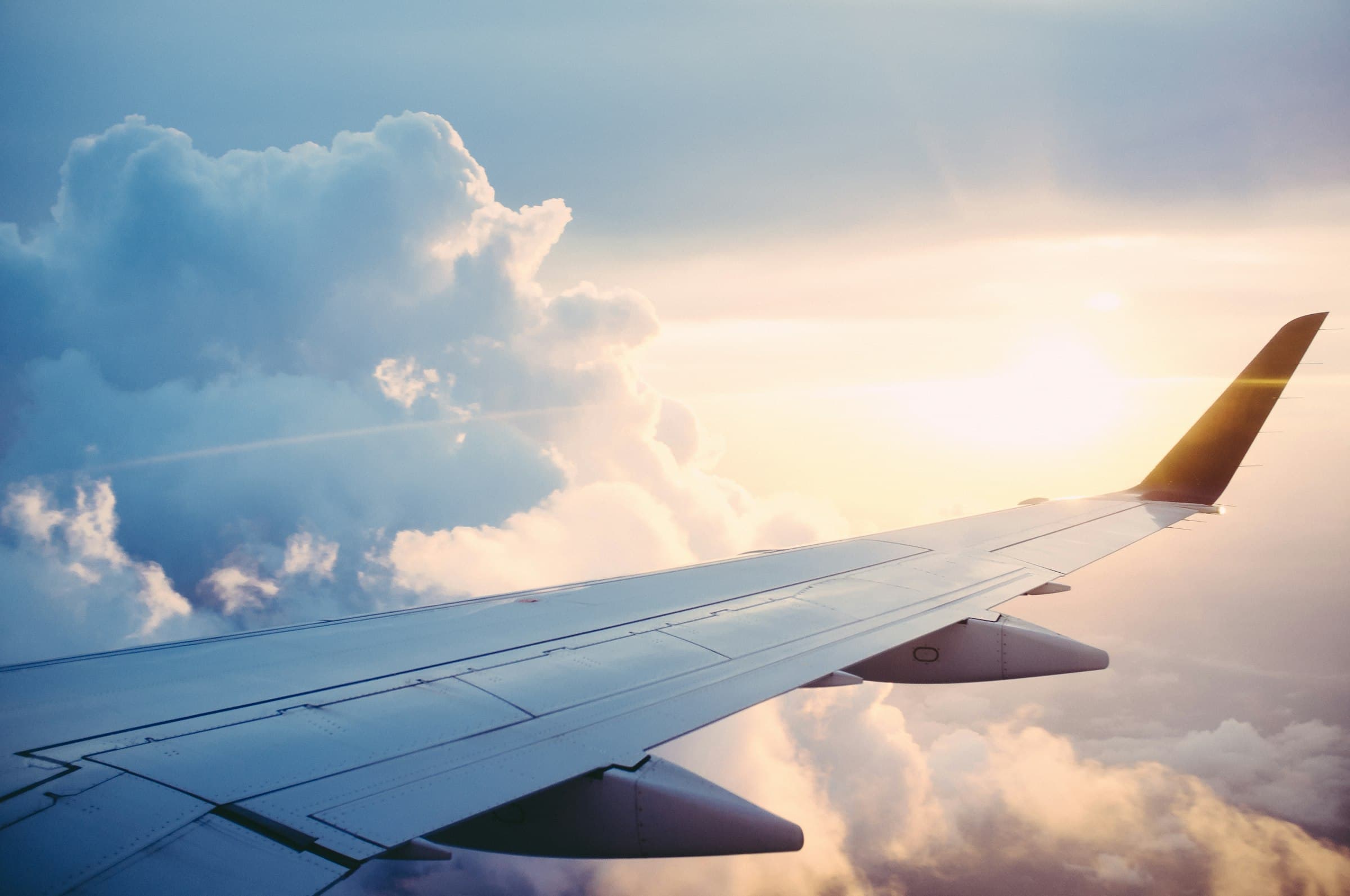 Ala de un avión sobre las nubes al atardecer